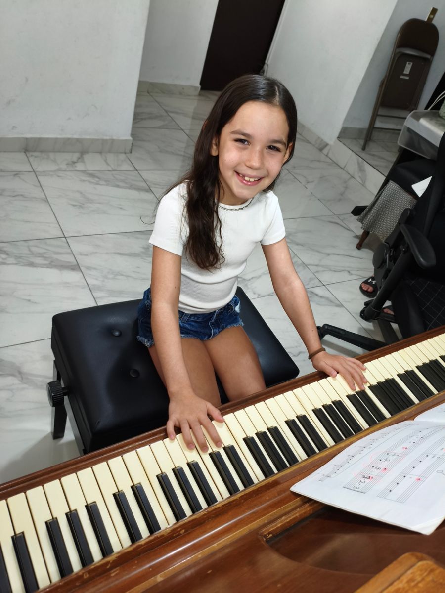 Una niña sonríe con las manos sobre el teclado del piano